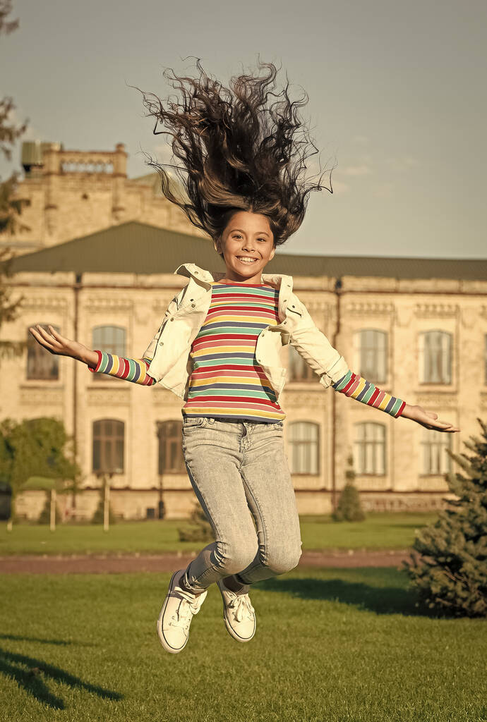 opravdové štěstí. přidat pohyb do svého života. Šťastné dítě skákající vysoko. pocit svobody. štěstí z dětství. malá dívka s kudrnaté vlasy skok venku. jarní prázdniny konečně. dítě oslavující úspěch - Fotografie, Obrázek