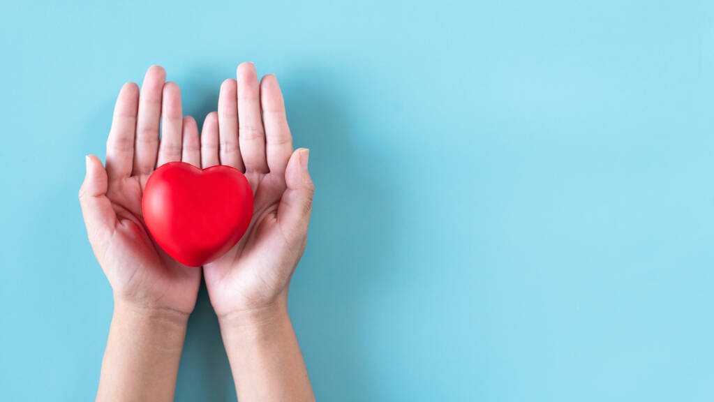 Ruce lidé drží červené srdce model na modrém backgroung, World heart day koncept - Fotografie, Obrázek