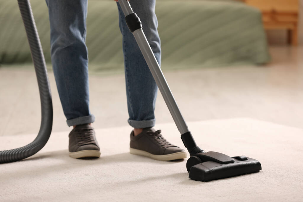 Homme nettoyage tapis avec aspirateur à la maison, gros plan - Photo, image