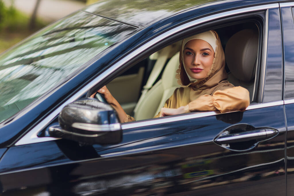 Mujer de Oriente Medio conduciendo un coche, mirando hacia el futuro. - Foto, Imagen