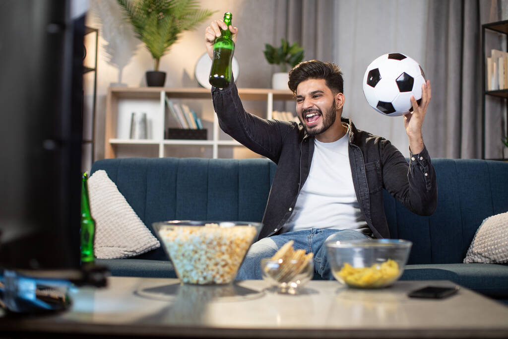 Χαρούμενος άνθρωπος βλέποντας ποδόσφαιρο στην τηλεόραση στο σπίτι - Φωτογραφία, εικόνα