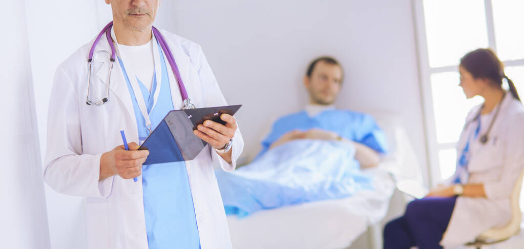 Médecin tenant un dossier devant un patient et un médecin - Photo, image