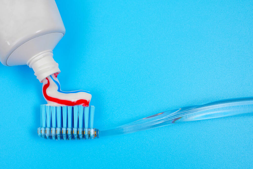 closeup της συμπίεσης οδοντόκρεμα στην οδοντόβουρτσα σε μπλε φόντο με αντίγραφο χώρο - Φωτογραφία, εικόνα