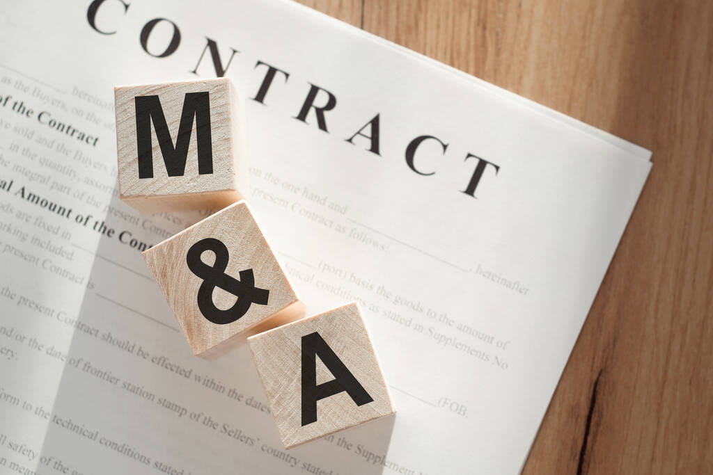 Word M&A (Mergers and Acquisitions) on wooden cubes on contract documents background. - Photo, Image