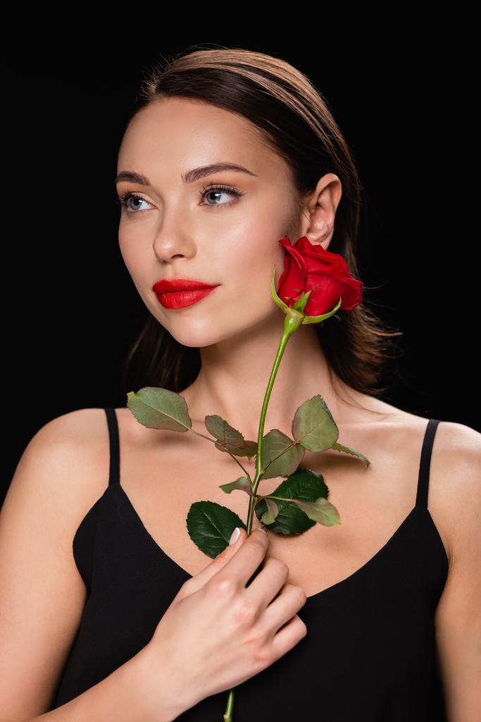 Hübsche Frau mit roter Rose schaut vereinzelt auf schwarz weg - Foto, Bild