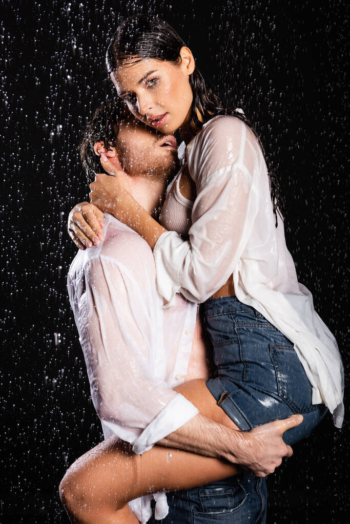 sexy romantyczna para w mokre ubrania namiętnie przytula w deszczu krople na czarnym tle - Zdjęcie, obraz