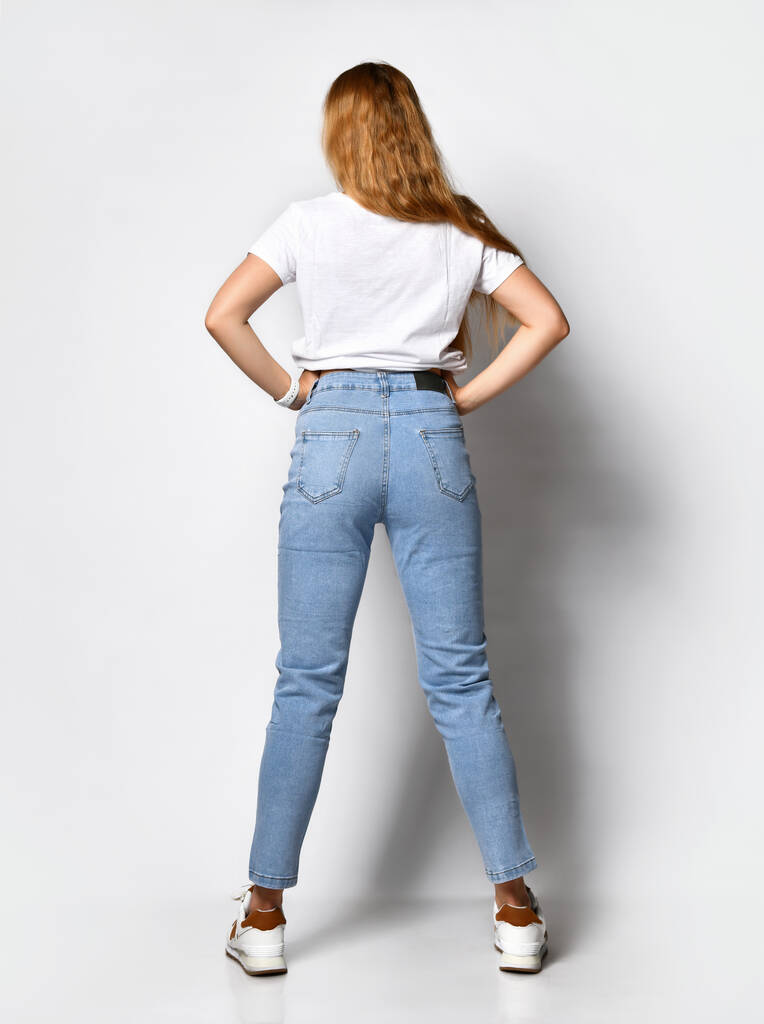 jeune femme maigre vêtue d'un jean bleu élégant et de baskets blanches. - Photo, image