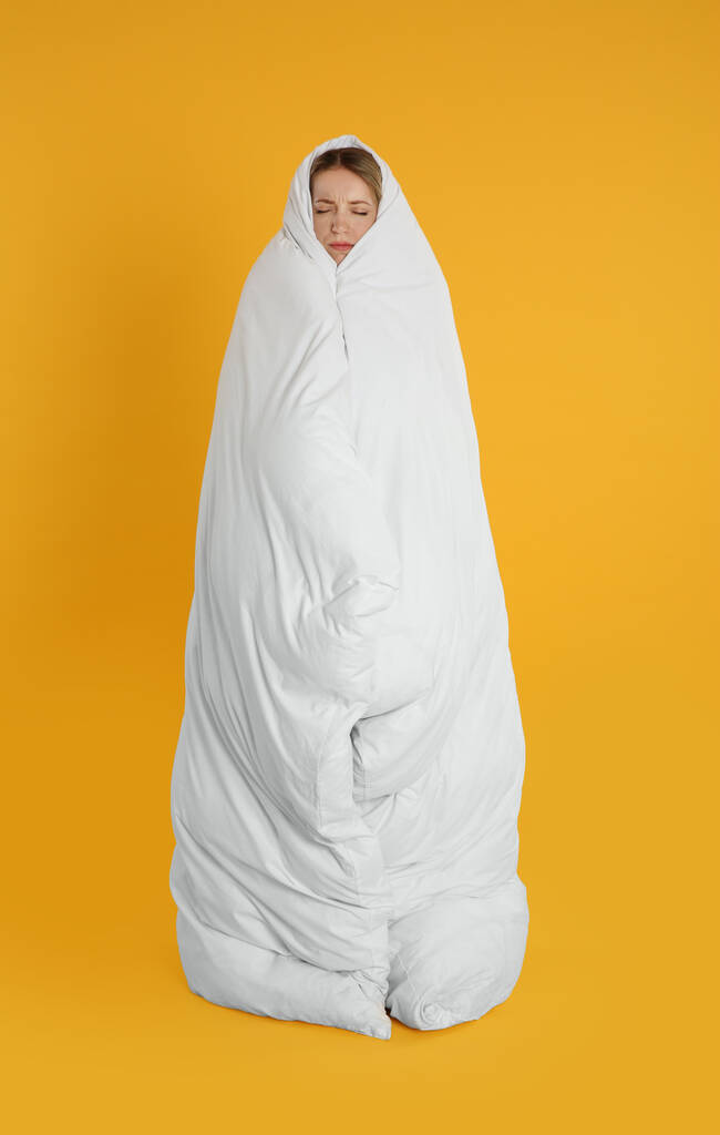 Junge Frau in weiche Decke auf gelbem Hintergrund gehüllt - Foto, Bild