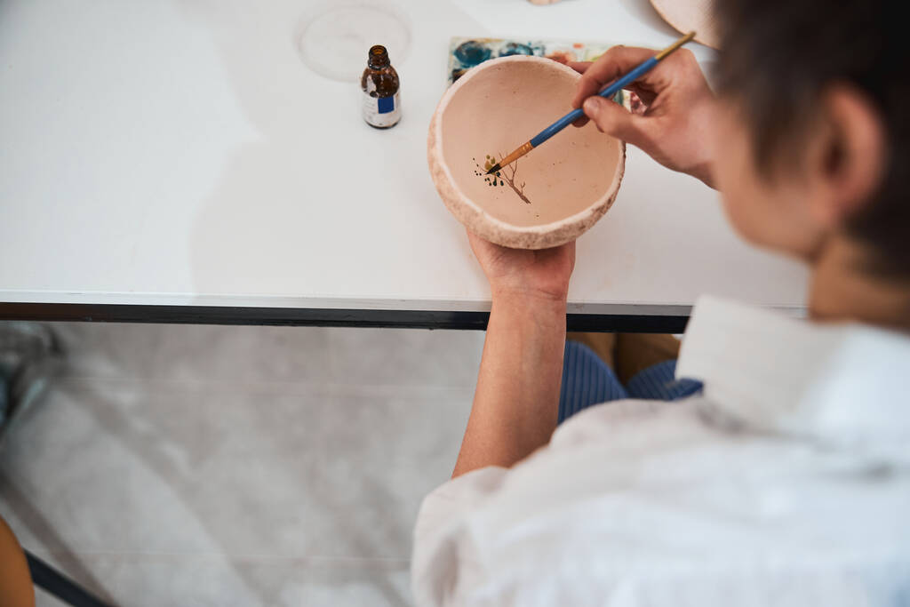 土鉢に木の葉を描く陶芸店の労働者 - 写真・画像