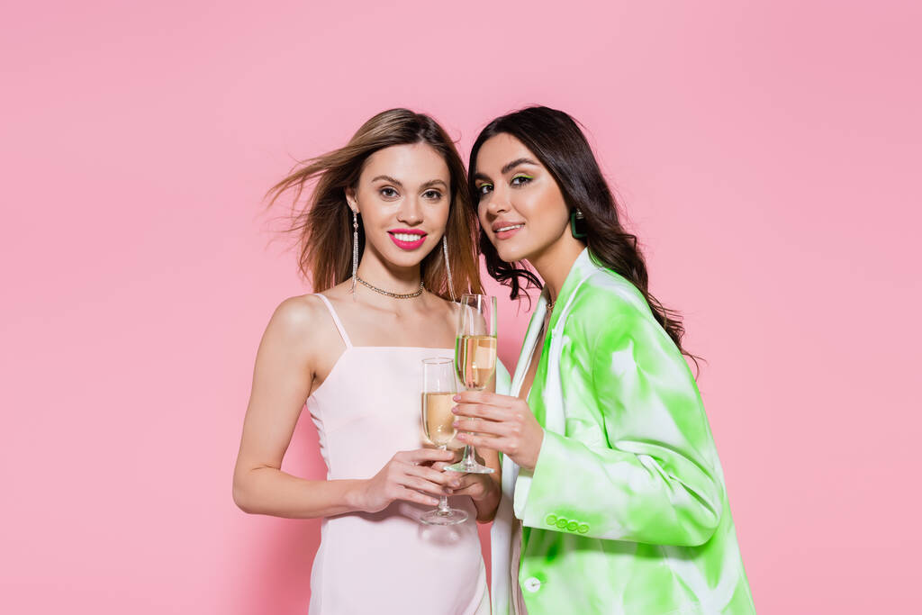 Mujeres bonitas sosteniendo copas de champán sobre fondo rosa  - Foto, Imagen