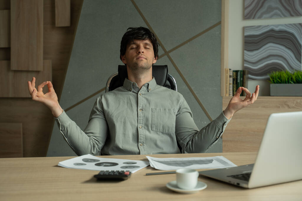 Der meditierende Mann im Büro bewältigt Stress. Führungskräfte machen Yoga am Schreibtisch in einem modernen Büro - Foto, Bild
