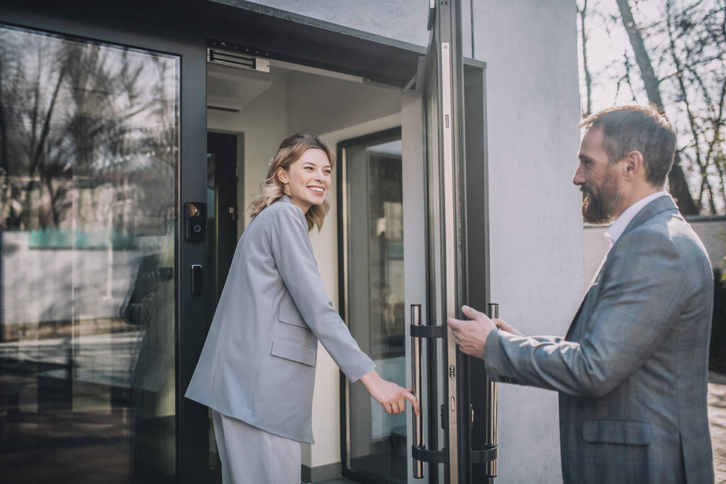 Mujer entrando a la oficina y hombre abriendo puerta - Foto, imagen