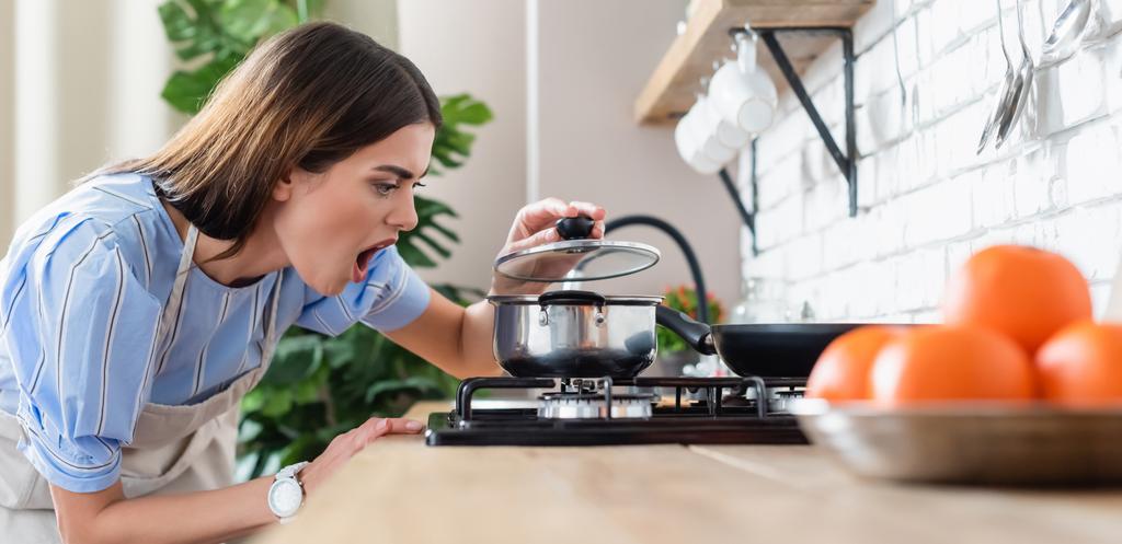 upset young adult woman cooking near burner in modern kitchen, banner - Photo, Image