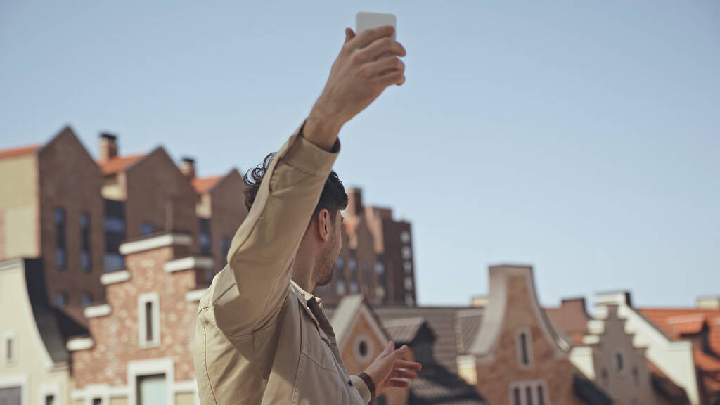 man holding smartphone while taking photo of buildings  - Photo, Image