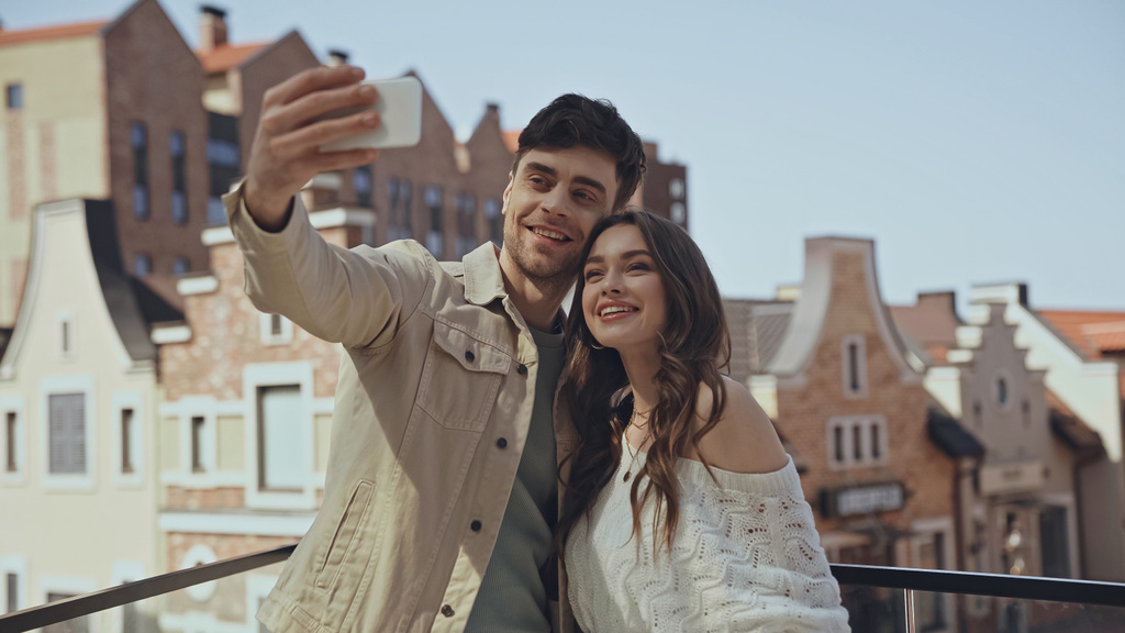 homem alegre tomando selfie com mulher feliz fora  - Foto, Imagem
