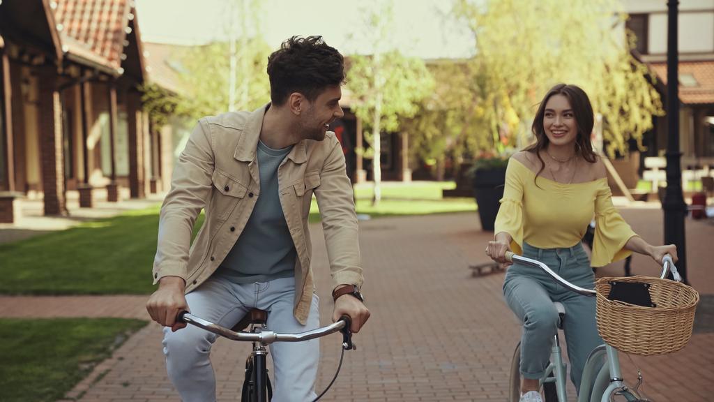 mosolygó férfi és nő biciklizés az utcán  - Fotó, kép