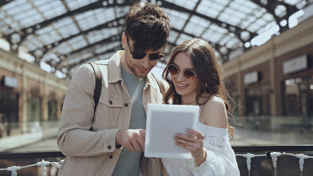 pareja en gafas de sol sonriendo mientras usa la tableta digital en el centro comercial  - Foto, Imagen