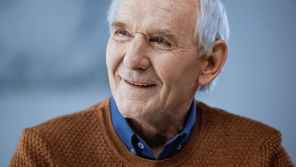portret van vrolijke oudere man wegkijkend op grijze achtergrond - Foto, afbeelding