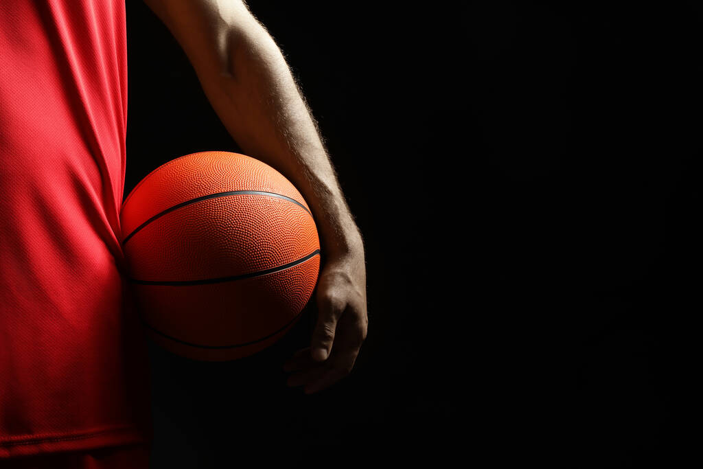 Jugador de baloncesto con balón sobre fondo negro, primer plano. Espacio para texto - Foto, Imagen