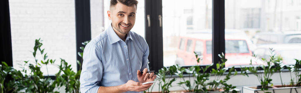 Θετικός επιχειρηματίας με στυλό κρατώντας smartphone, banner  - Φωτογραφία, εικόνα