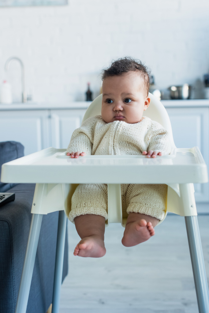criança afro-americana sentada em cadeira de bebê na cozinha - Foto, Imagem