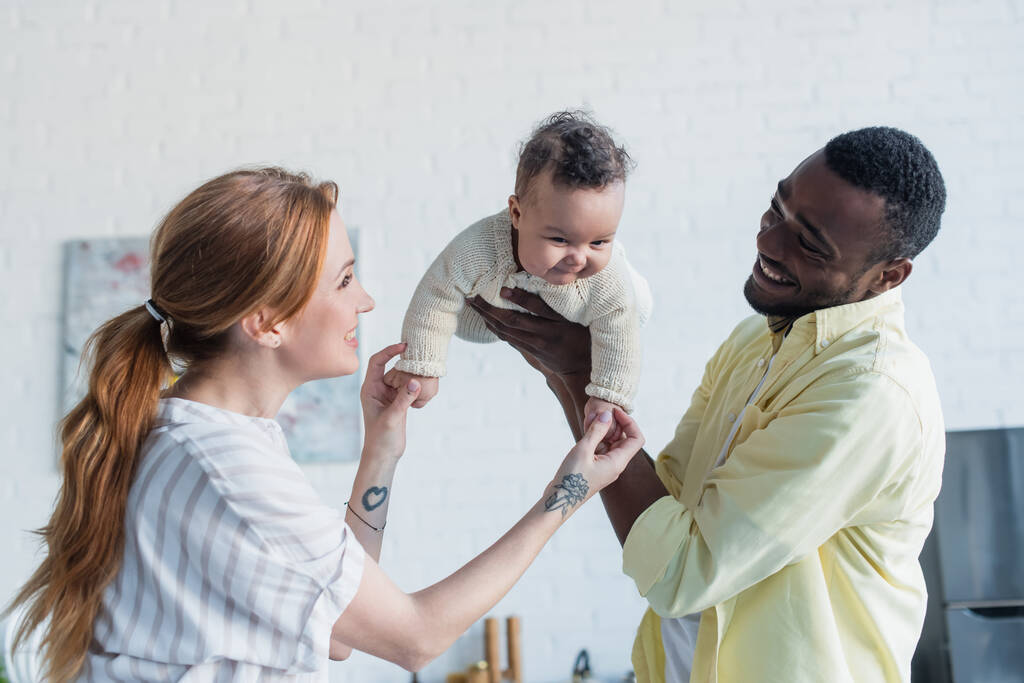happy multicultural couple having fun with baby girl at home - Photo, Image