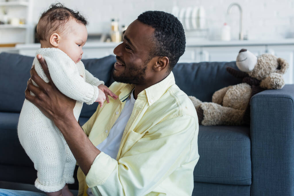 felice uomo afro-americano che tiene la figlia neonata a casa - Foto, immagini