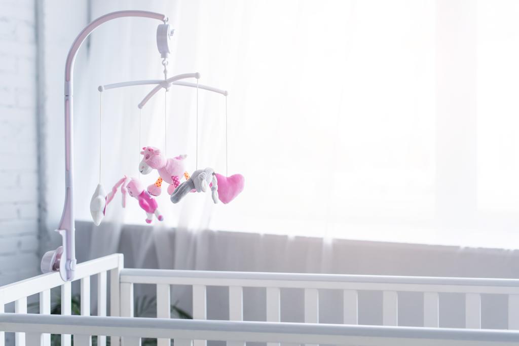 soft toys hanging over crib in nursery near window - Photo, Image
