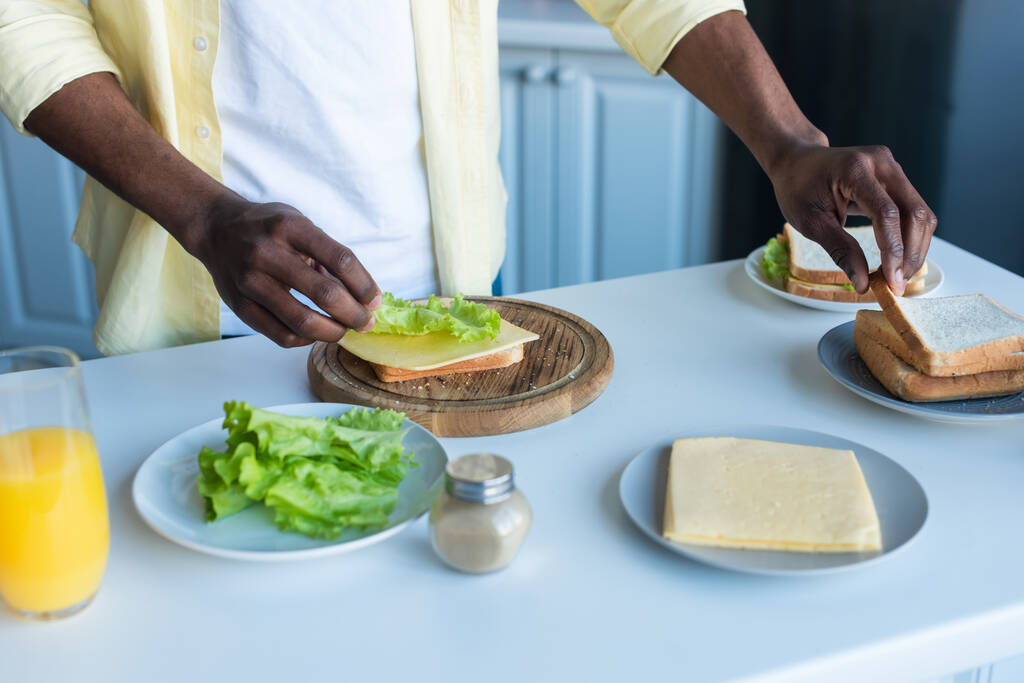 Afro-Amerikan bir adamın mutfakta sandviç hazırladığını gördüm. - Fotoğraf, Görsel