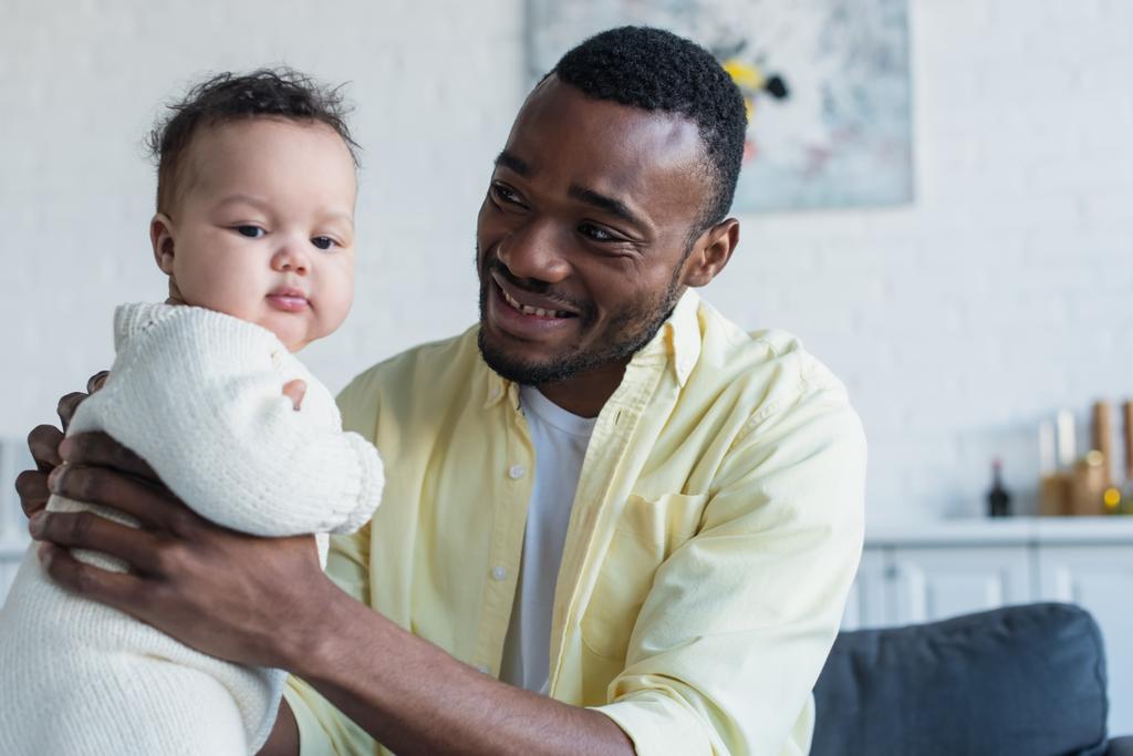 piacere uomo holding africano americano bambino ragazza a casa - Foto, immagini
