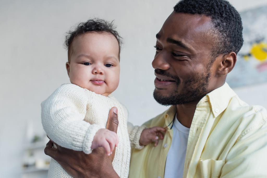 joyeux homme afro-américain tenant fille bébé souriante - Photo, image