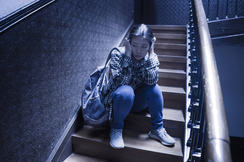 młoda piękna Azjatka cierpiąca na depresję - dramatyczny portret na schodach smutnej i przygnębionej Japonki jako ofiary znęcania się i znęcania  - Zdjęcie, obraz