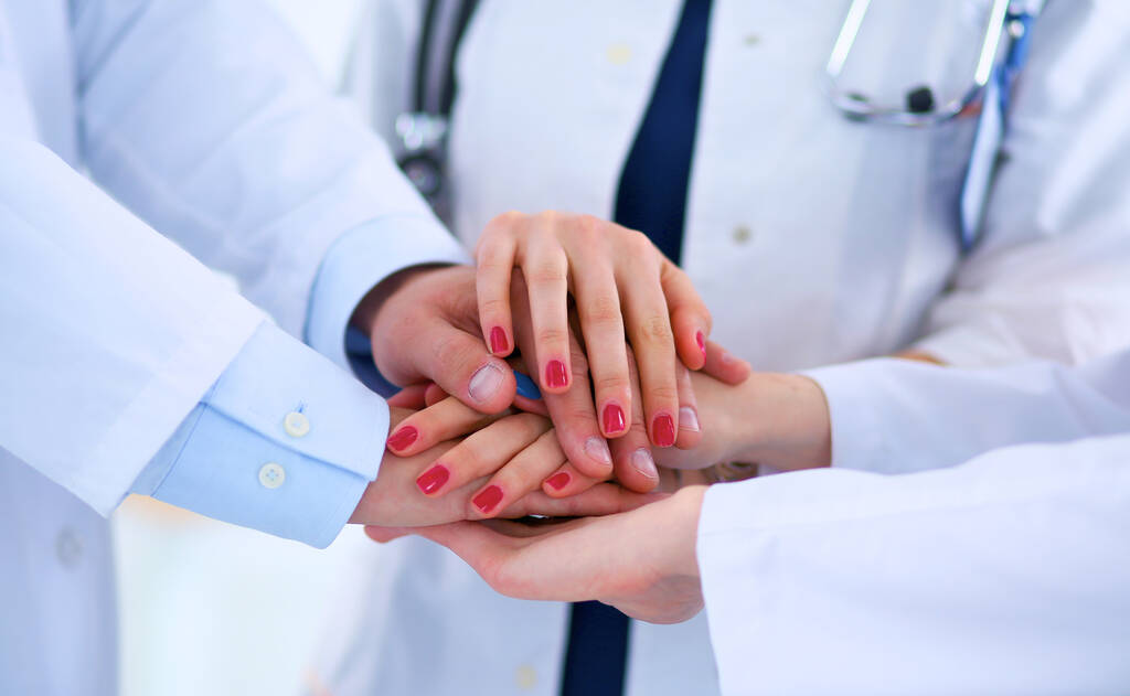 Médicos y enfermeras en un equipo médico apilándose las manos - Foto, Imagen