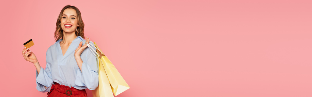 Όμορφη γυναίκα κρατώντας τσάντες για ψώνια και πιστωτική κάρτα σε ροζ φόντο, πανό  - Φωτογραφία, εικόνα