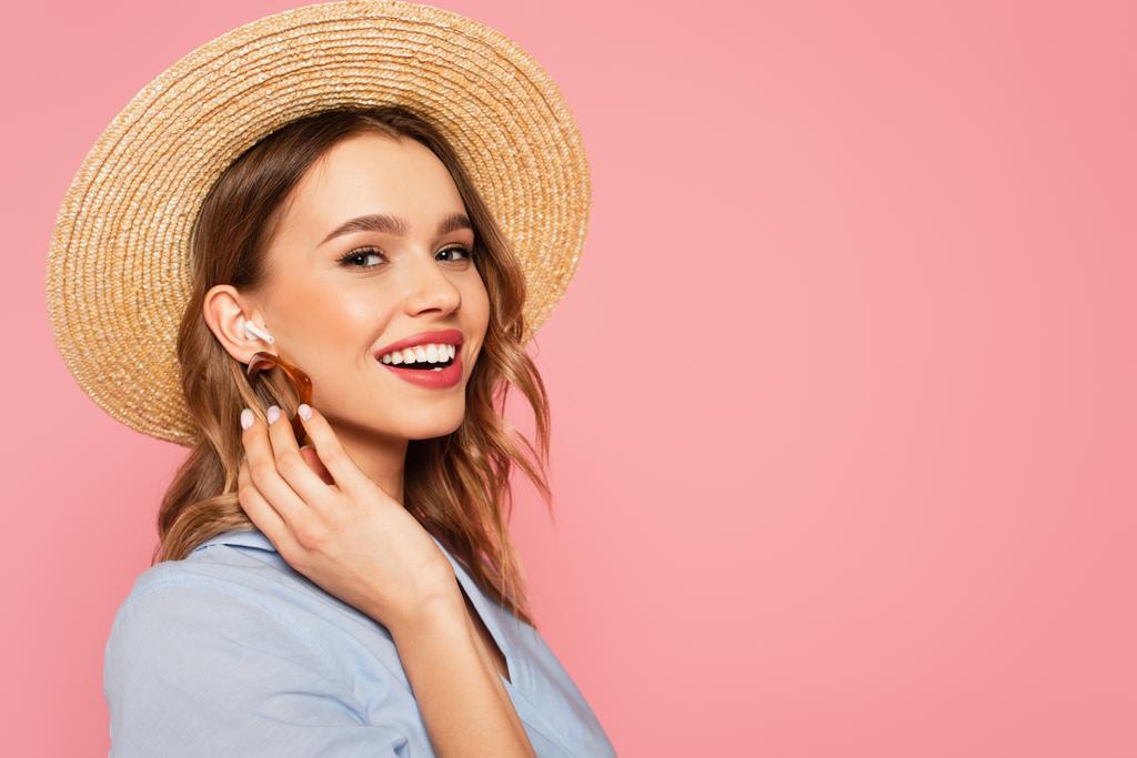 Pretty woman in sun hat listening music in earphone isolated on pink  - Photo, Image