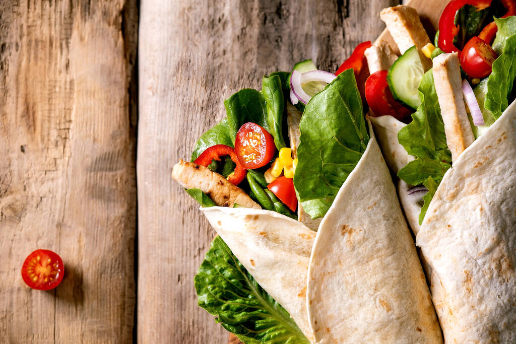Traditional mexican tortila wrap with pork meat and vegetables over brown wooden background. Top view, flat lay. Copy space. Homemade fast food - Foto, Imagem