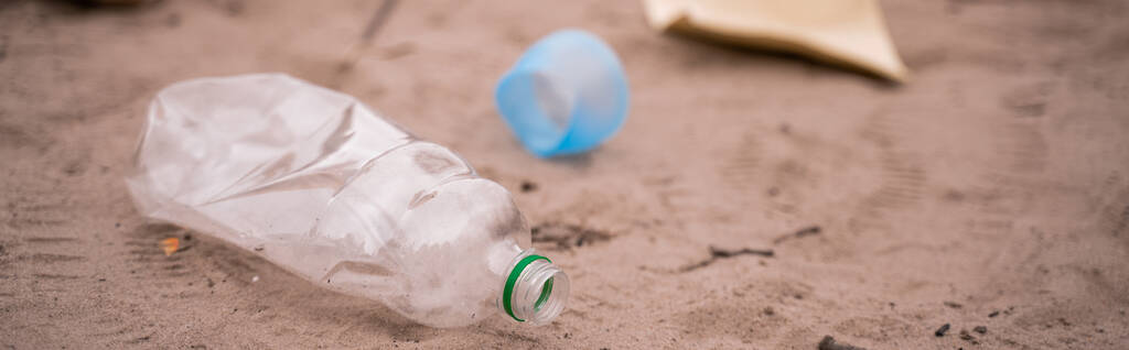 muovipullo roskakorin lähellä hämärtyneellä hiekalla, banneri - Valokuva, kuva