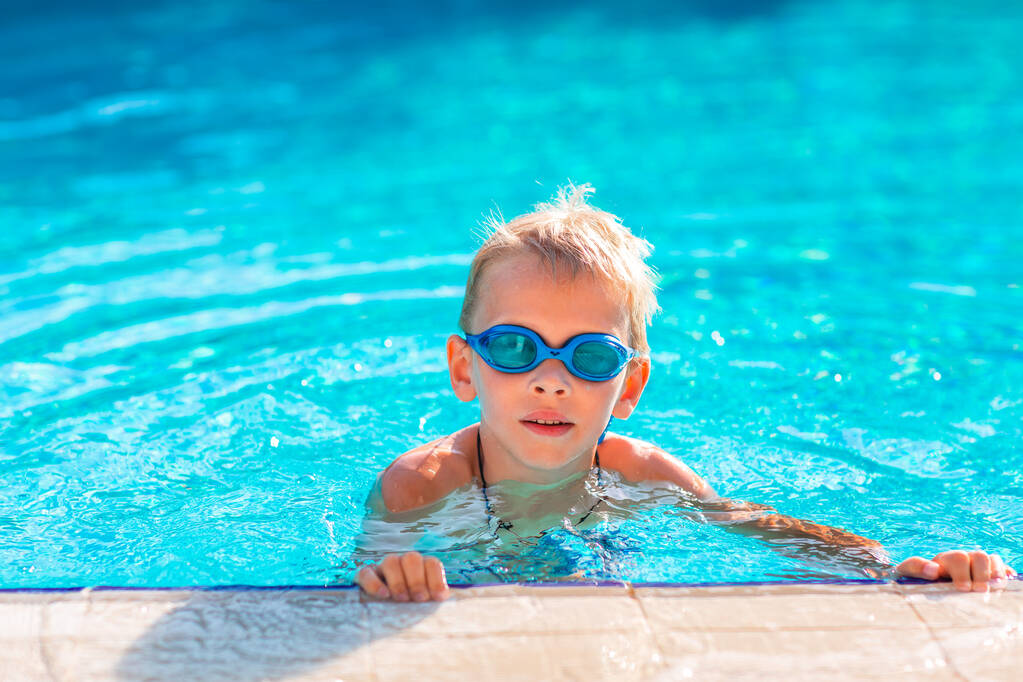Милий щасливий маленький хлопчик в окулярах плаває і крутить у басейні. Концепція плавання для дітей
 - Фото, зображення