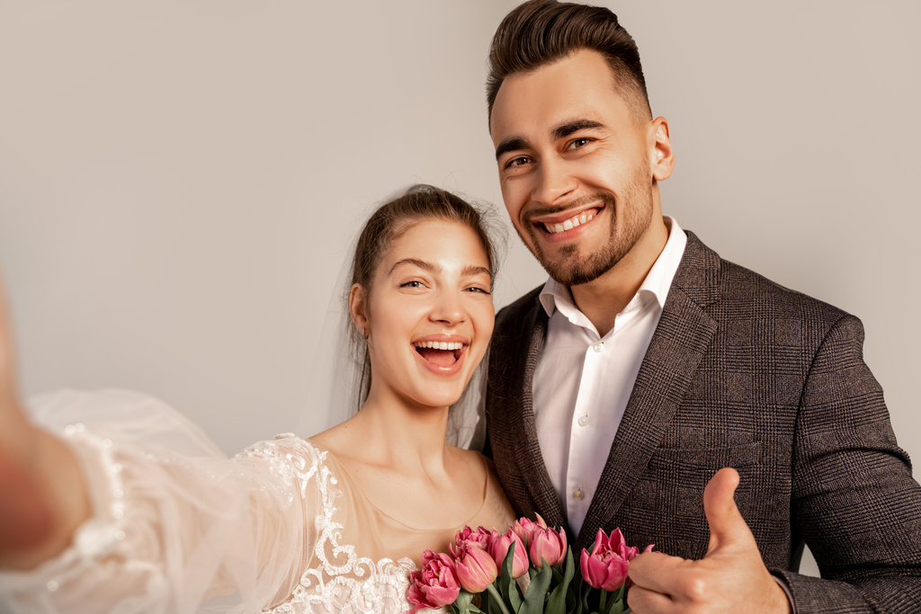 happy man showing thumb up near excited bride isolated on grey - 写真・画像
