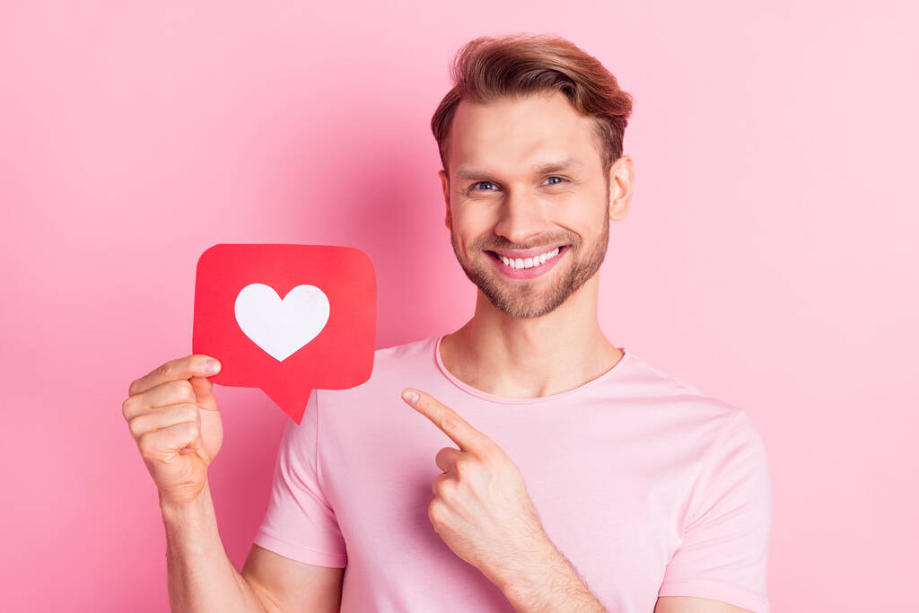 Retrato de homem alegre indicar dedo segurar papel como cartão isolado no fundo cor-de-rosa - Foto, Imagem