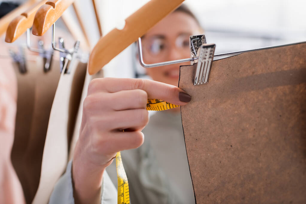 Размытый дизайнер измеряет рисунок шитья на вешалке в ателье   - Фото, изображение