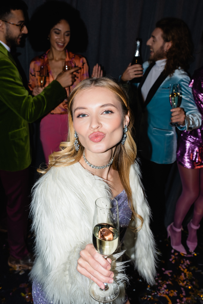 jeune femme adulte boudant lèvres avec verre de champagne sur la fête avec des amis interracial sur fond gris - Photo, image