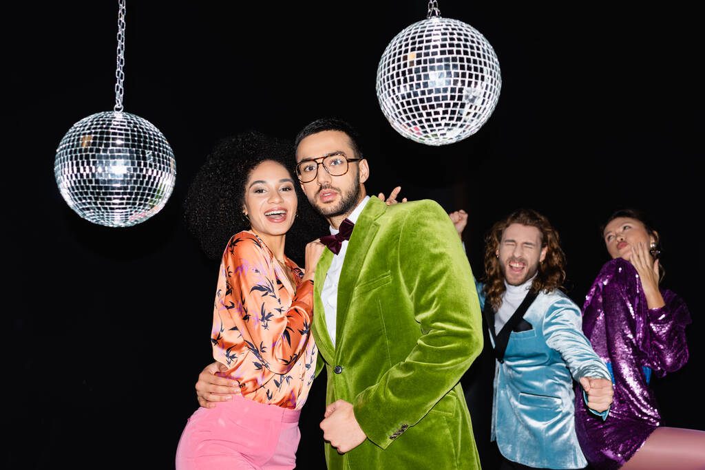 смешные многорасовые друзья в красочной одежде танцуют в ночном клубе на черном фоне - Фото, изображение