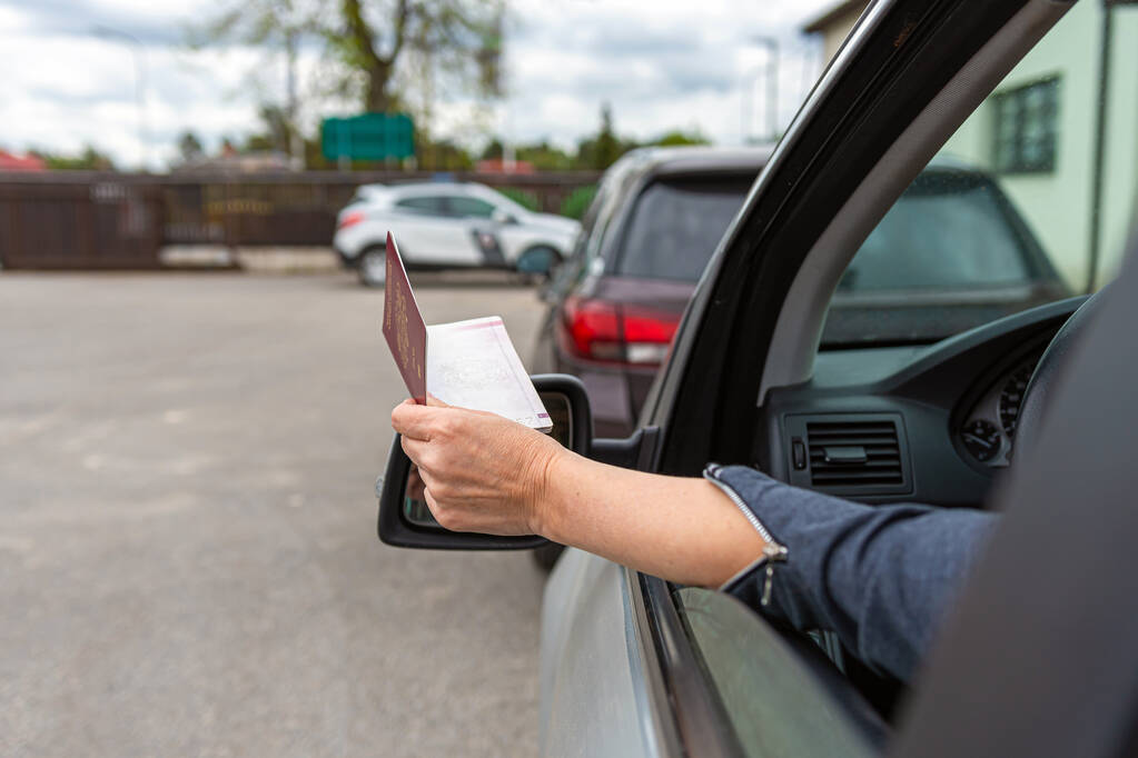 женщины вручают через окно автомобиля паспорт для таможенного контроля, водитель с удостоверением личности в автомобиле на пограничном контрольно-пропускном пункте - Фото, изображение