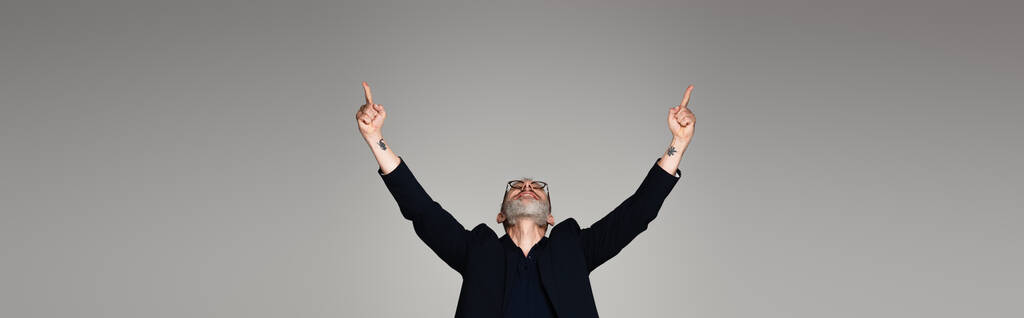 muž středního věku v brýlích a obleku ukazuje prsty na šedou, banner - Fotografie, Obrázek