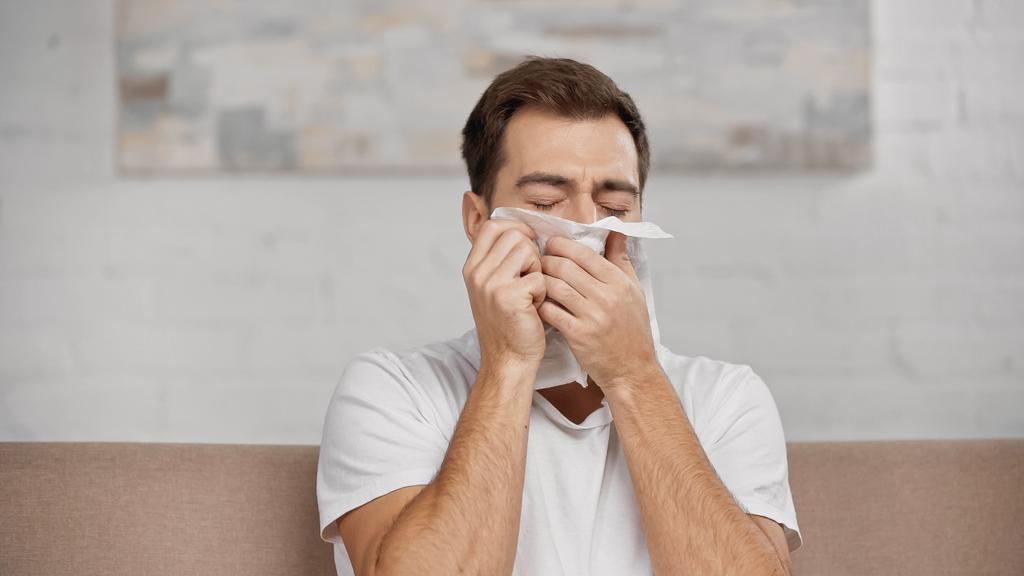allergic man sneezing in napkin at home  - 写真・画像