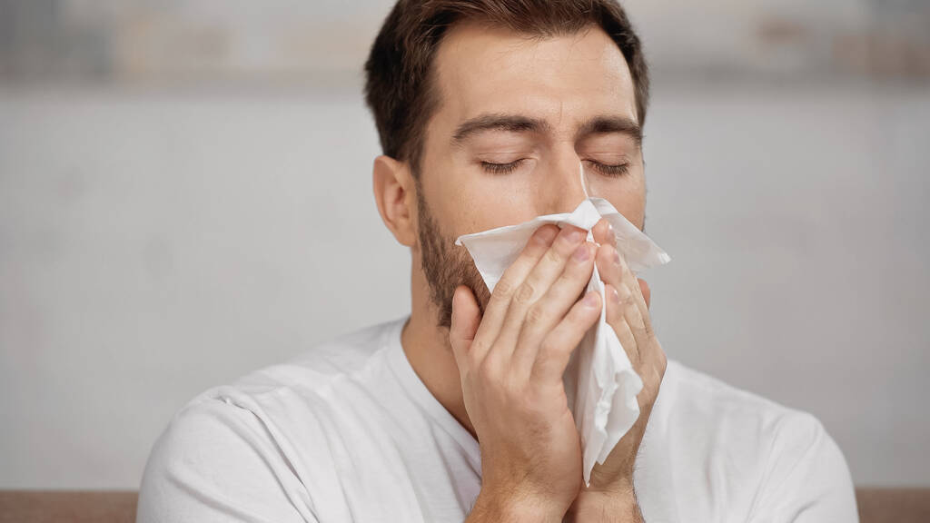 man with allergy sneezing in tissue at home - Foto, Imagem