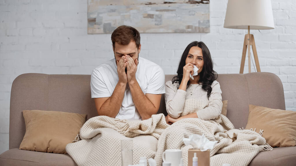 Krankes Paar niest und hustet im Wohnzimmer  - Foto, Bild