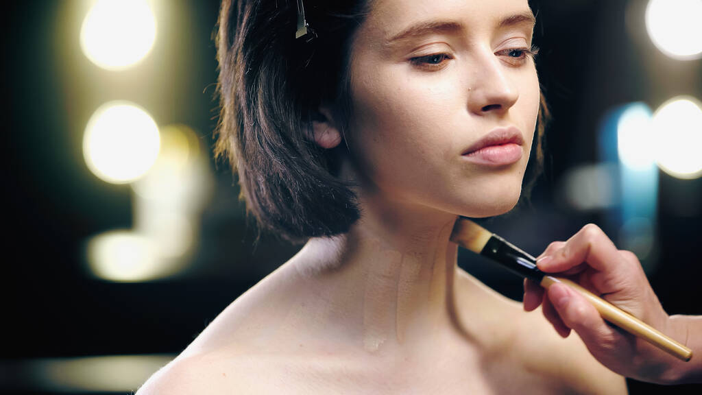 make-up kunstenaar aanbrengen stichting op hals van model met cosmetische borstel - Foto, afbeelding
