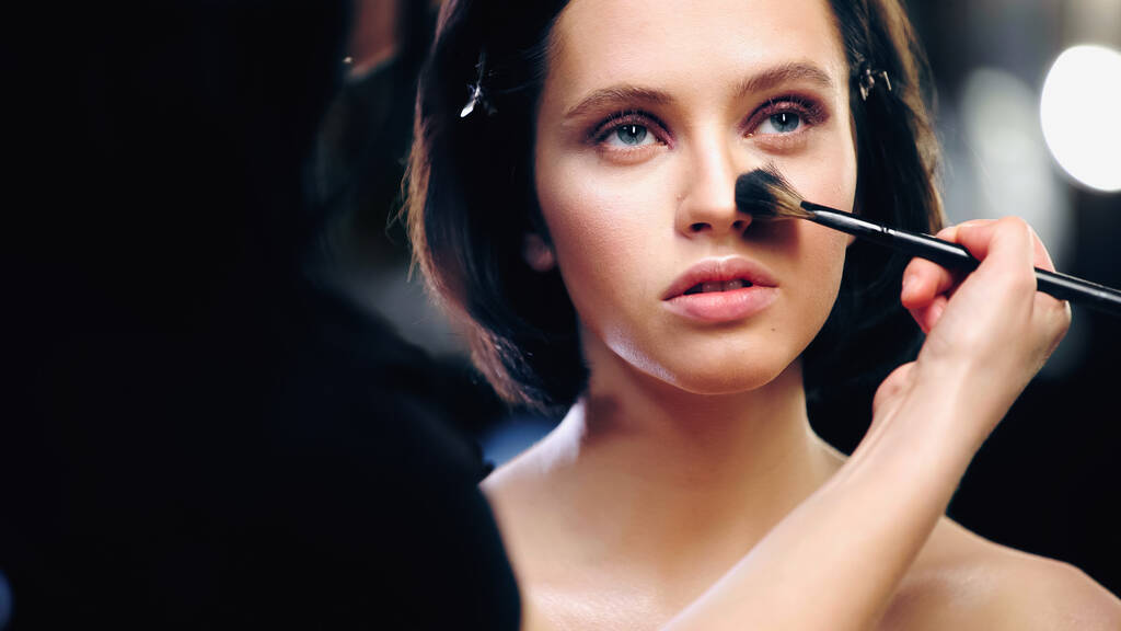 make-up kunstenaar aanbrengen van gezicht poeder op gezicht van model  - Foto, afbeelding
